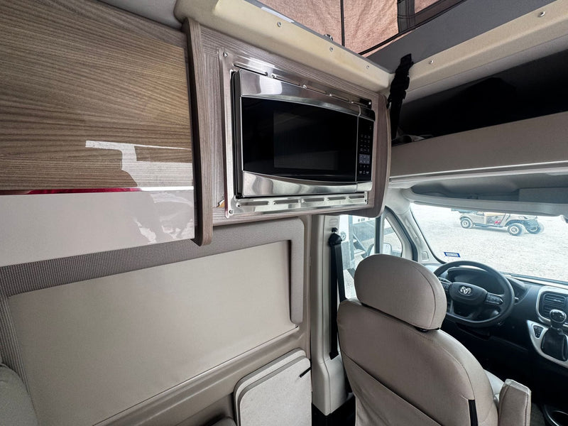 RV rental with a sleek, built-in microwave, modern wood-grain cabinetry, and comfortable driver's seat. — photo 5