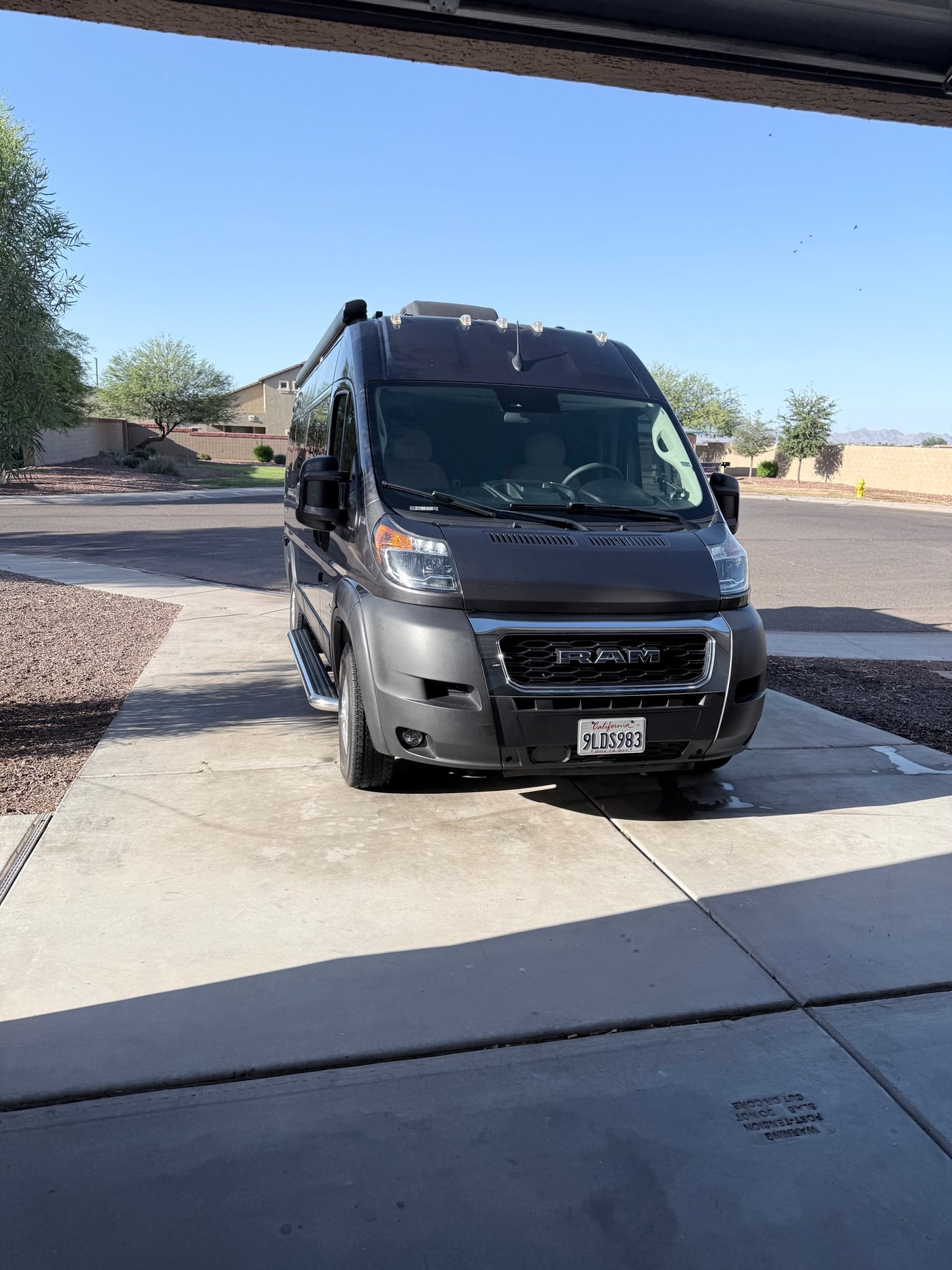 An RV rental, a dark gray Ram ProMaster van with California plate 9LDS983, parked in a sunny driveway. Ready for travel! — photo 6
