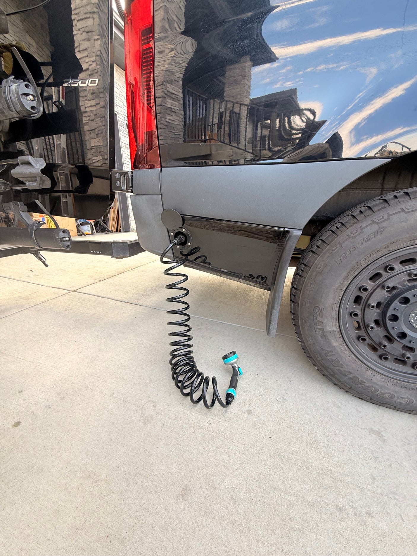Black rv rental camper van with external shower hookup and coiled hose, ready for adventure cleanup.