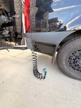 Black rv rental camper van with external shower hookup and coiled hose, ready for adventure cleanup.