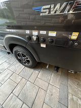 RV rental side with utility connections: cable TV, city water, Furrion electrical, and solar input. Tire visible on paved ground.