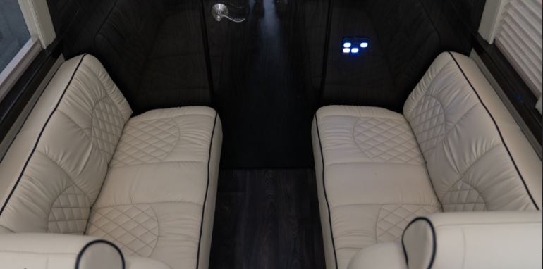 Inside an RV rental: Cream-colored, quilted seating and dark wood floors define this luxury interior with controls.