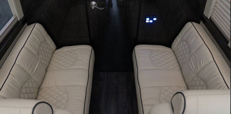 Inside an RV rental: Cream-colored, quilted seating and dark wood floors define this luxury interior with controls.
