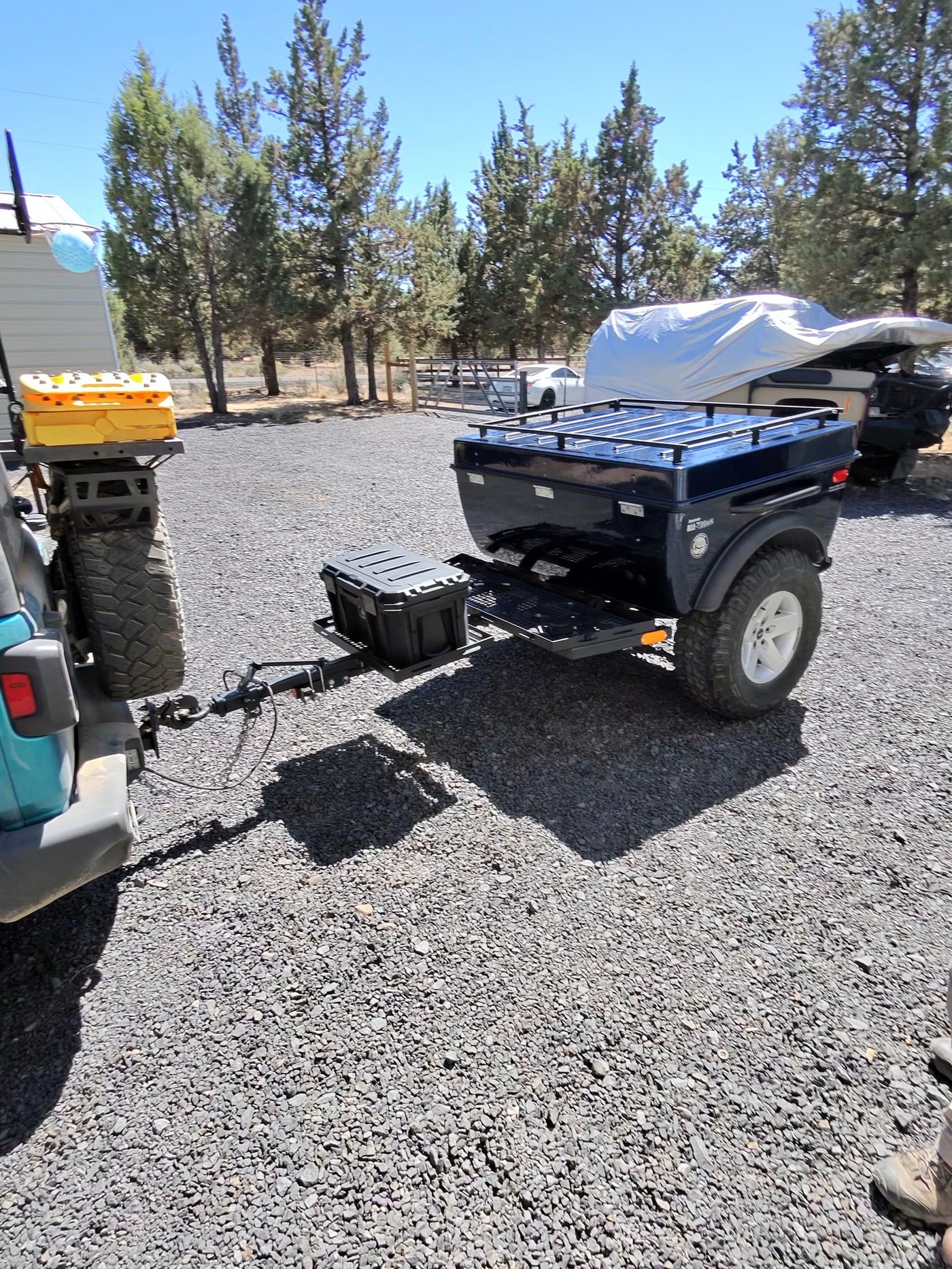 Adventure ready! Teal Jeep towing a rugged off-road utility trailer with storage boxes on a gravel lot. Ideal for rv rental camping trips. — photo 5