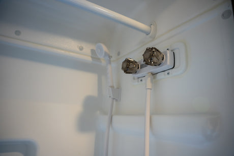 RV rental shower: a compact white shower stall with handheld showerhead and dual control knobs.