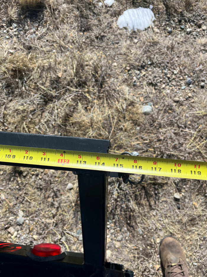 Measuring an RV rental component with a tape measure, showing inches from 109 to 119 on a metal beam.