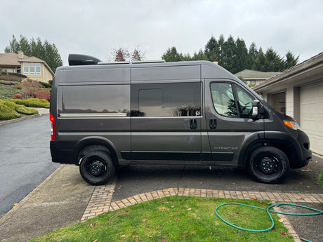 Dark gray camper van with rooftop AC, ideal for RV rental and road trips. Side text: DAVE & MATT VANS.