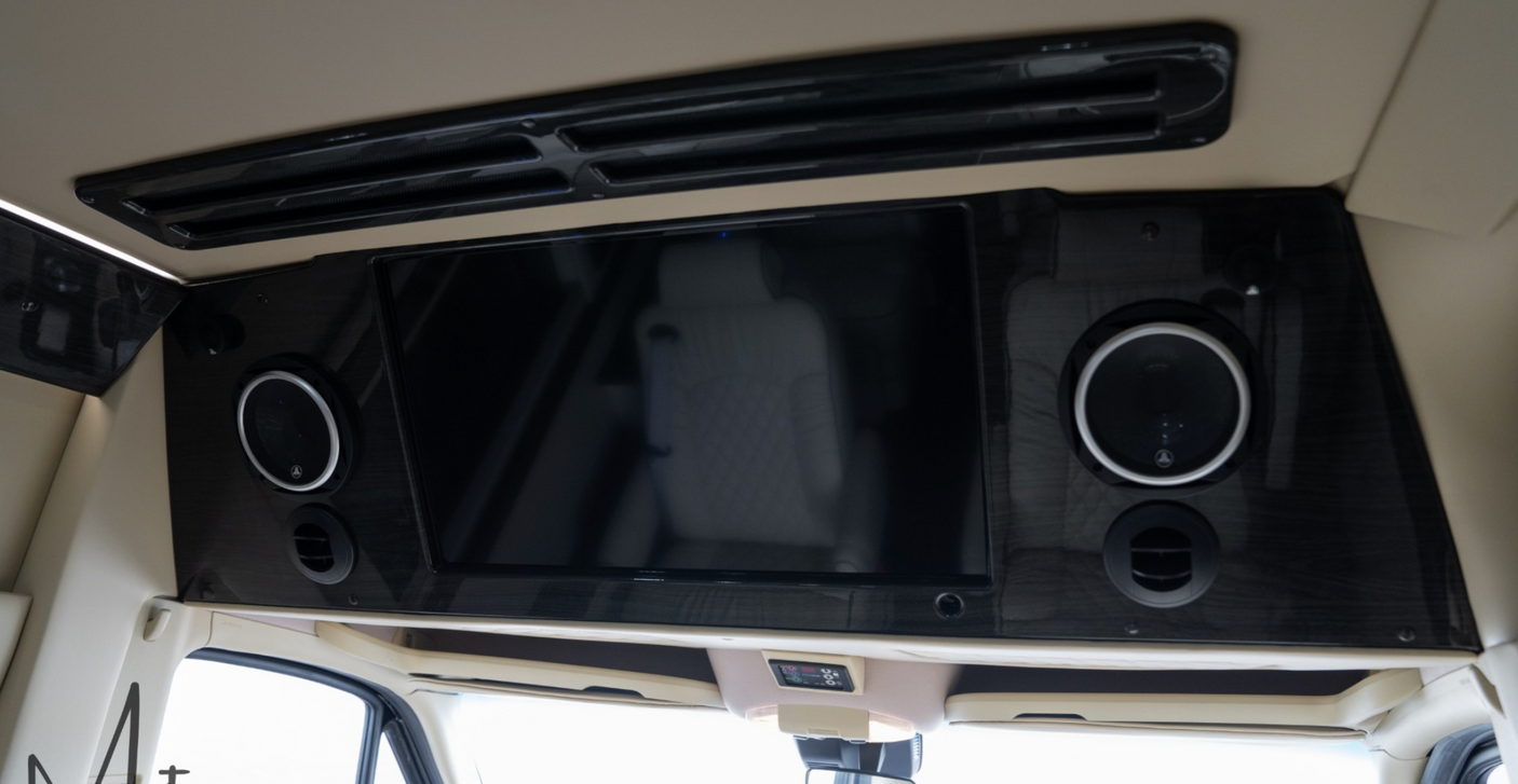 Luxury RV rental interior showcasing a mounted TV, premium speakers, and AC vents for comfortable travel and entertainment.