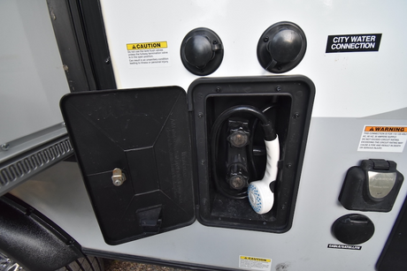 RV rental external utility connections: an open outdoor shower, city water, electrical, and cable/satellite hookups.