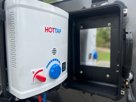 An open black case reveals a white HOTTAP portable water heater, featuring red/blue controls for your RV rental hot showers.