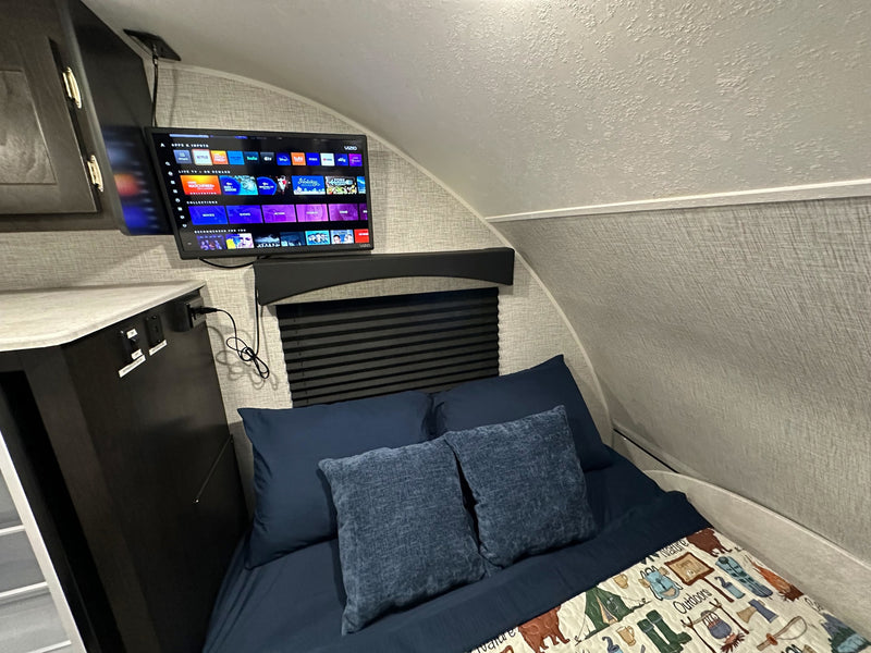 Cozy RV rental bedroom with a mounted TV showing streaming options, a comfortable bed, and a nature-themed blanket. — photo 17
