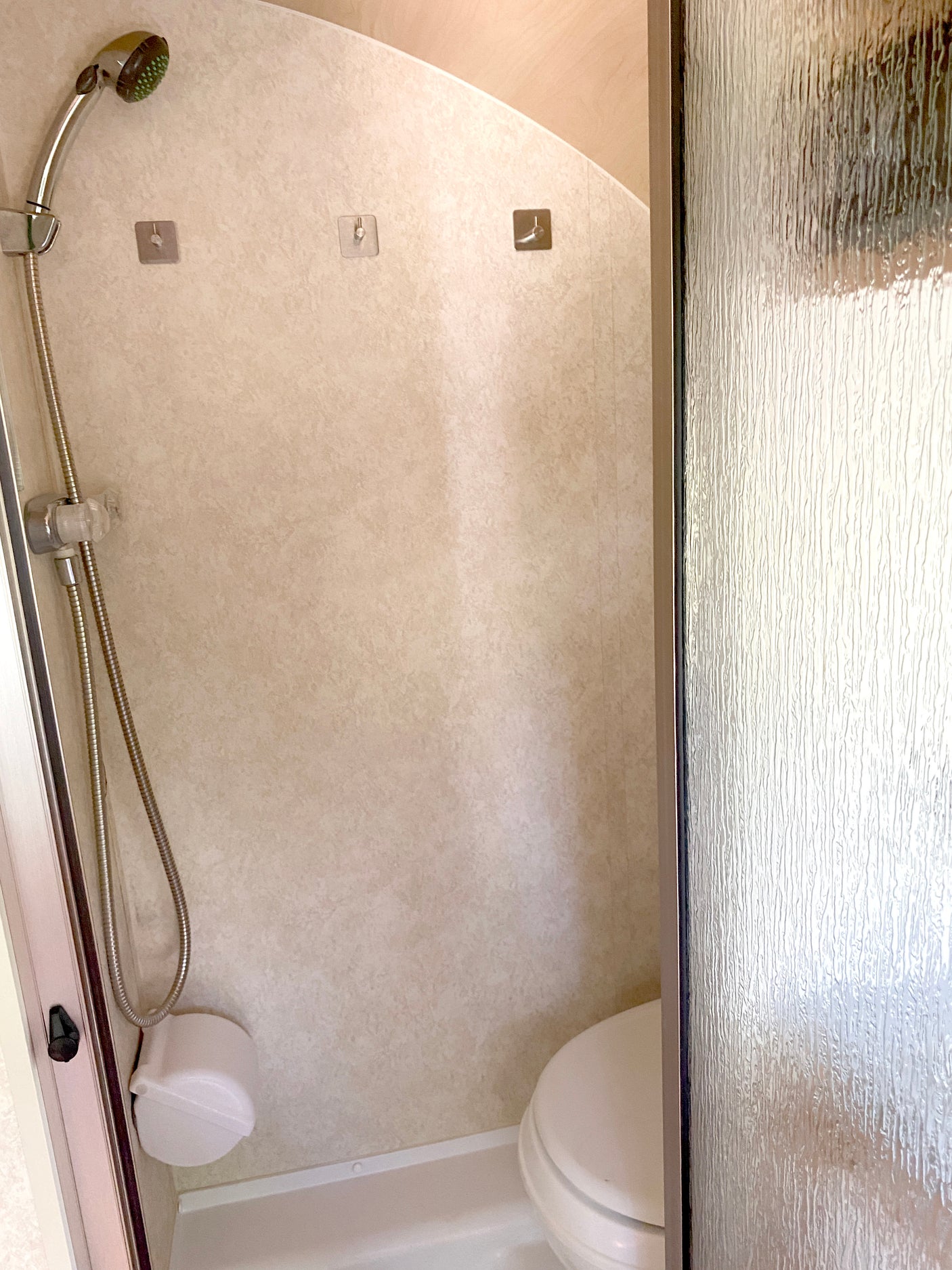 This RV rental wet bath includes a handheld shower, compact toilet, and adhesive hooks, optimized for small spaces and travel.