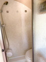 This RV rental wet bath includes a handheld shower, compact toilet, and adhesive hooks, optimized for small spaces and travel.