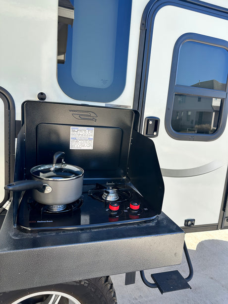 RV rental with an outdoor kitchen setup. A pot sits on the Suburban cooktop attached to the Flagstaff camper.