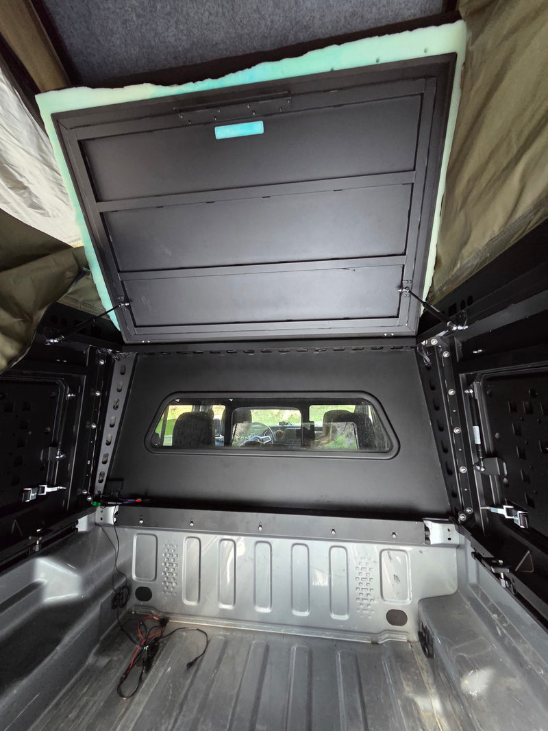 Interior view of a truck bed with an open pop-top camper, featuring a sleeping platform. Perfect for your next rv rental adventure! — photo 8