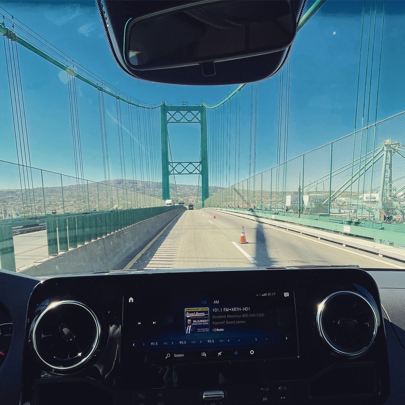 Driving an RV rental on a sunny day! Dashboard view of a green suspension bridge and 101.1 FM radio. A great road trip.
