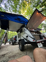 FREESOLO teardrop RV rental & SUV with rooftop tent set up at a leafy campsite for outdoor adventure.
