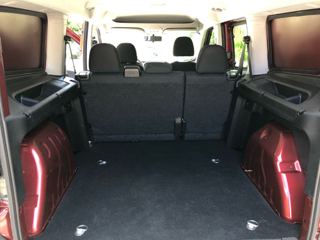 Looking into the spacious cargo area of an RV rental, featuring rear seats, side storage, & floor tie-downs.