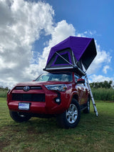 Red SUV with purple rooftop tent deployed, ready for **RV rental** camping adventures on Kauai.
