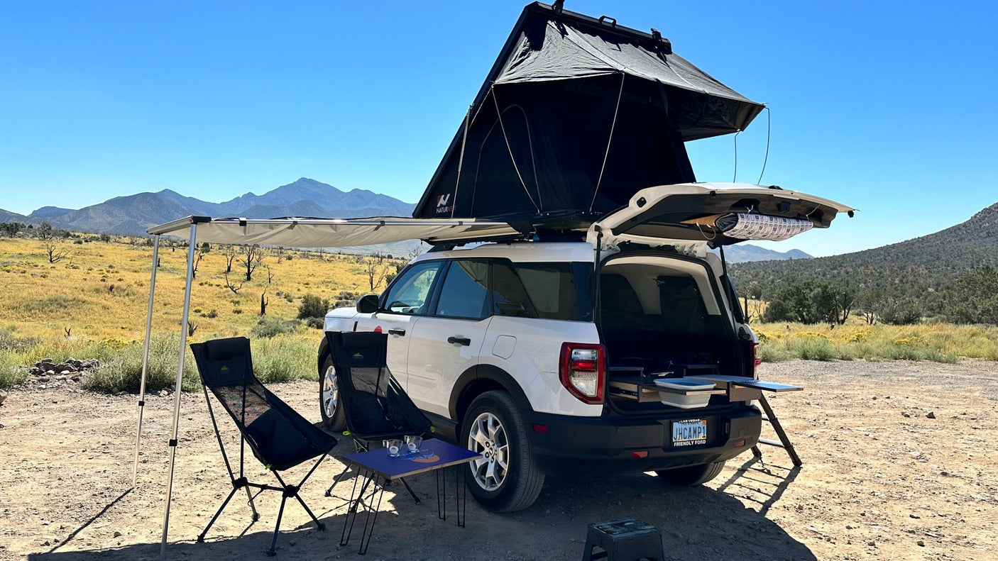 Explore the outdoors! This Bronco Sport RV rental is set for car camping with a rooftop tent, awning, & pull-out kitchen in a desert.
