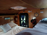 Bright RV rental interior with comfortable beds, a ceiling vent, and a variety of charming beach decor.