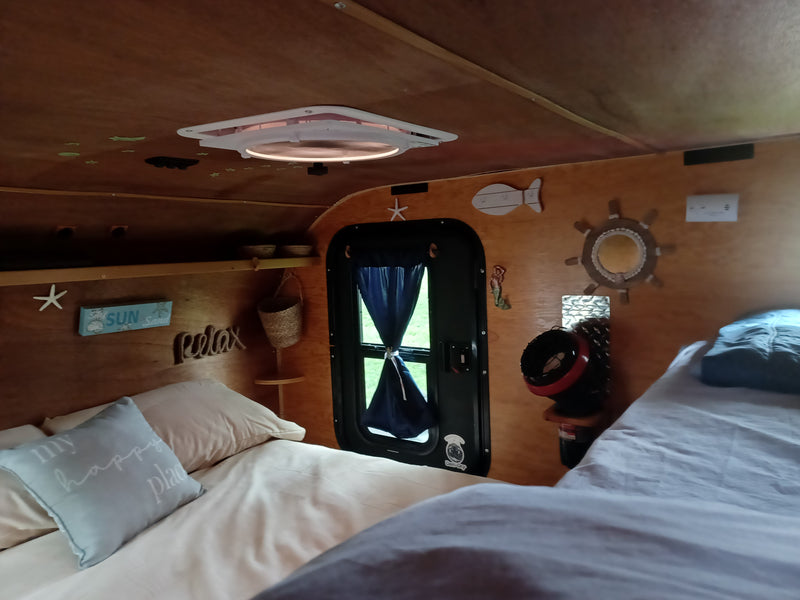Bright RV rental interior with comfortable beds, a ceiling vent, and a variety of charming beach decor. — photo 14