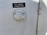 White RV rental exterior with a black "CITY WATER CONNECTION" label and water inlet, plus a door hinge on the right.