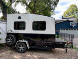 A sleek black and white Alpine compact travel trailer with a utility deck, ready for your next RV rental adventure.