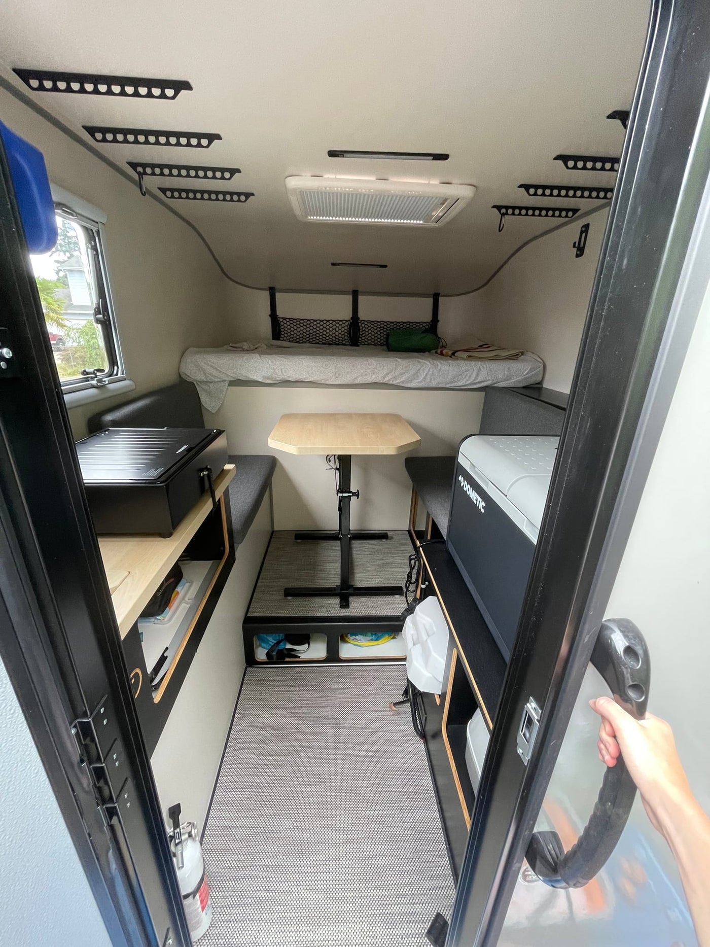  parked on a dirt path amidst junipers under cloudy skies.|Enjoying the outdoors with an RV rental truck camper at a woodsy campsite. Features a picnic table — photo 5