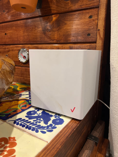 Compact Verizon router in an RV rental interior, on decorative tiles next to wood paneling & a gauge, for mobile internet.
