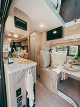 Stylish rv rental interior: compact kitchen, cozy dining, and modern amenities for a comfortable travel experience.