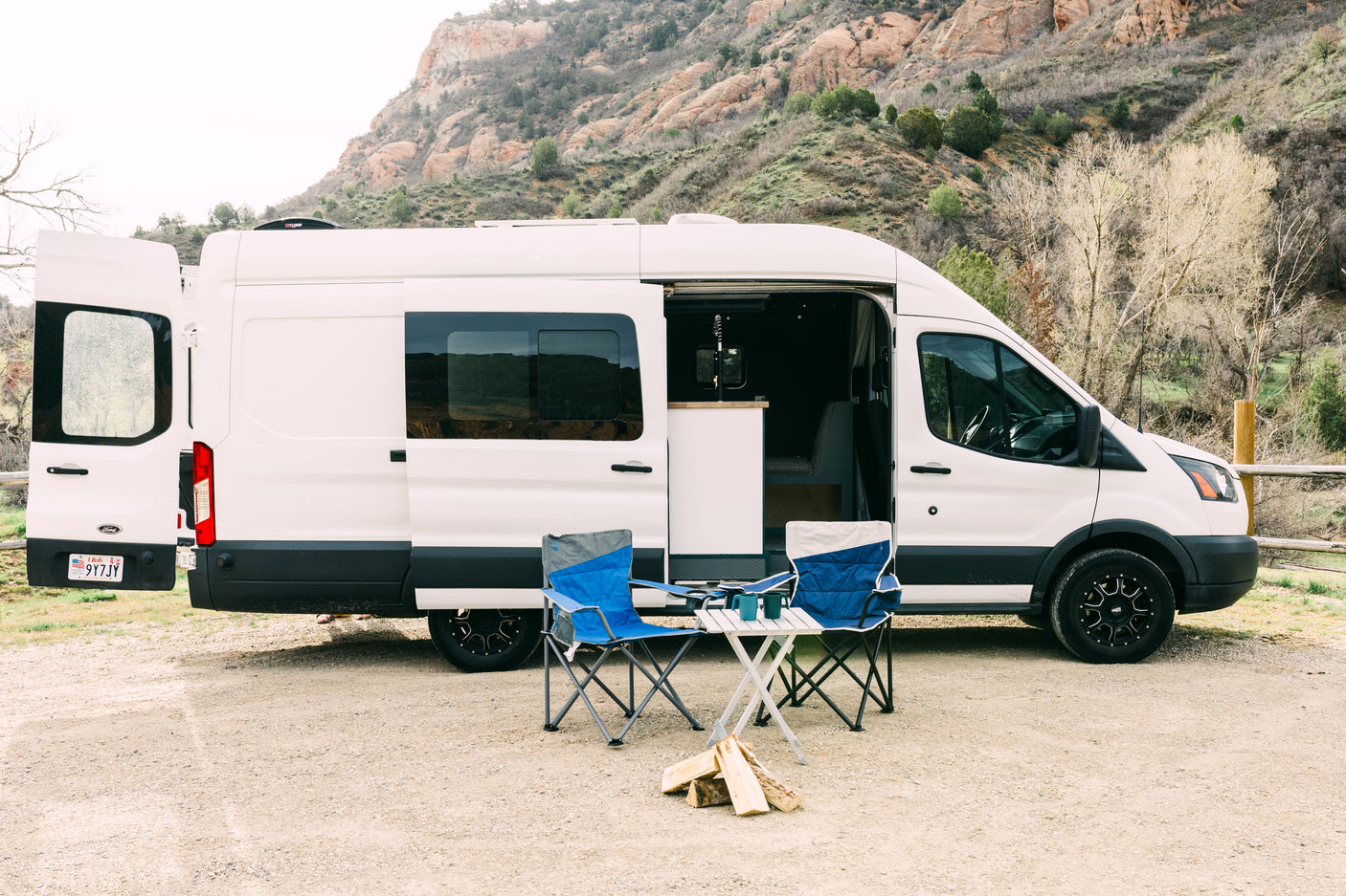 An RV rental camper van in Utah, parked with camping chairs & firewood, ready for an outdoor escape in the mountains.
