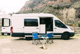 An RV rental camper van in Utah, parked with camping chairs & firewood, ready for an outdoor escape in the mountains.