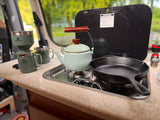 RV rental kitchen with a kettle, cast iron pan, Stanley coffee maker, and spice grinder for camping.