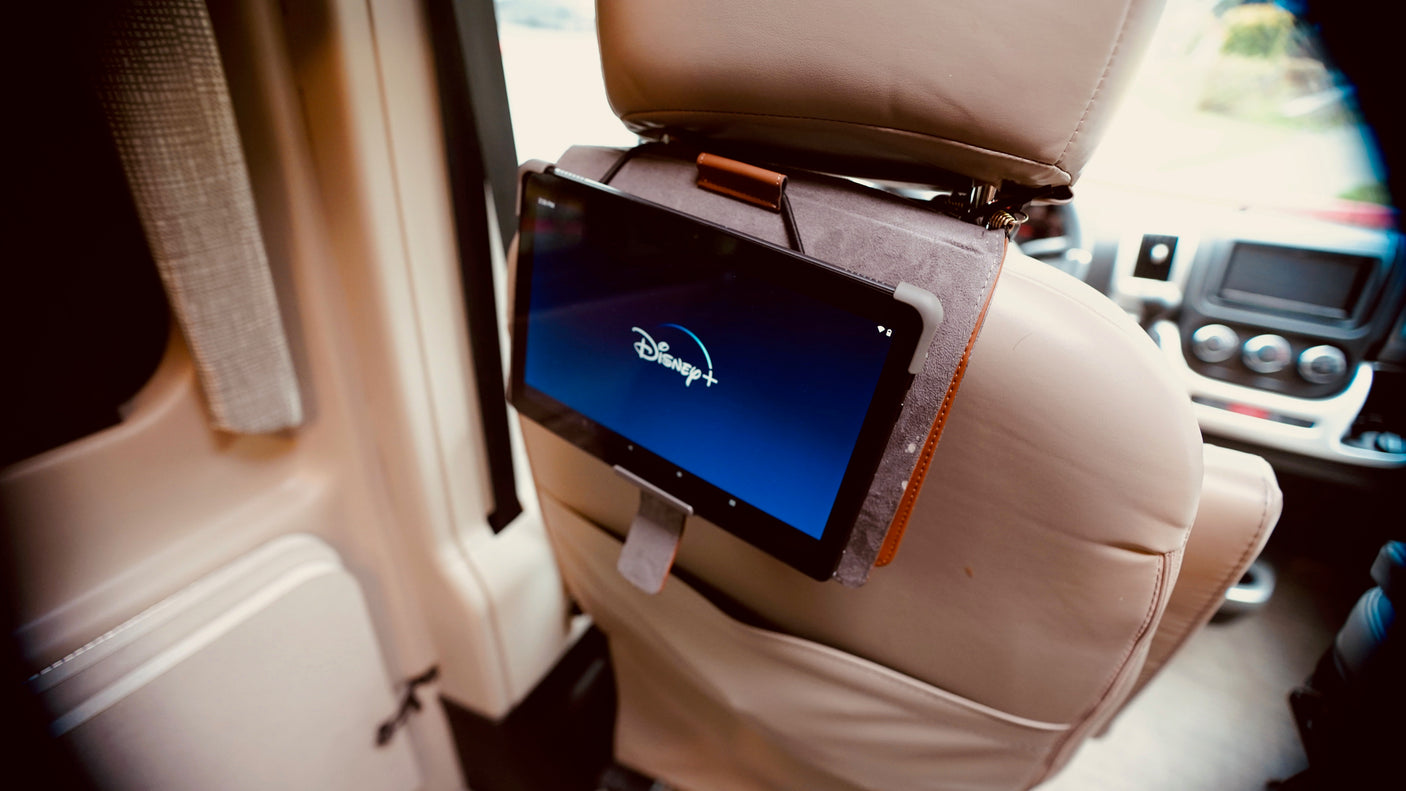 Inside an RV rental: A tablet displaying Disney+ is mounted on a seat's headrest, ideal for travel entertainment.