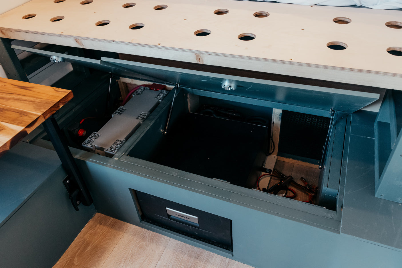 RV rental: Open under-bed storage revealing the large battery system & Dometic fridge/cooler.
