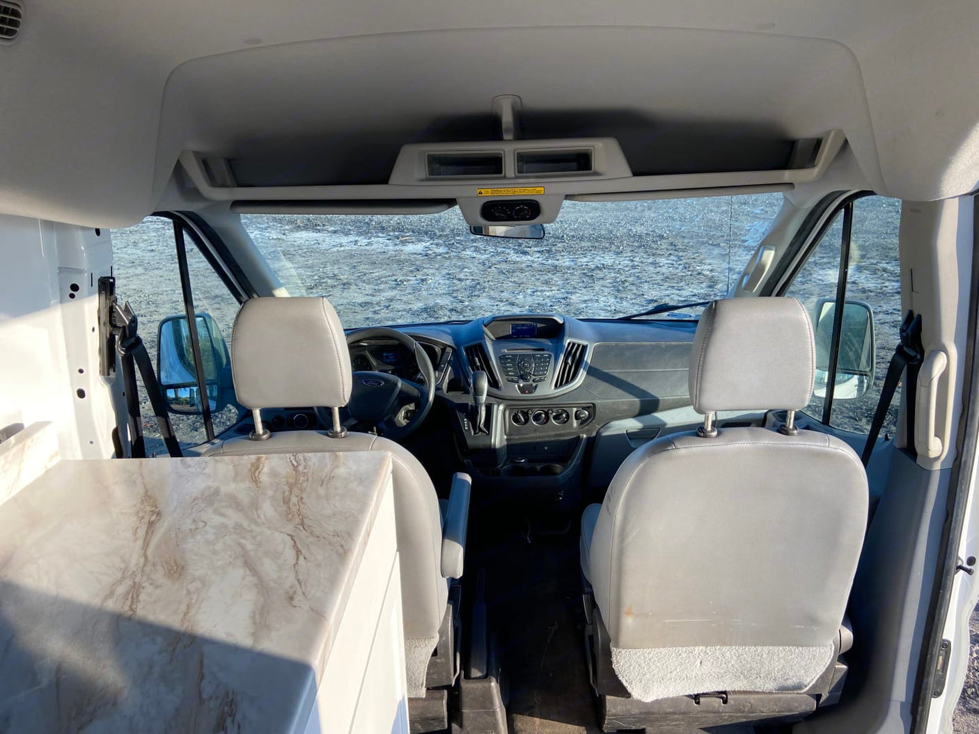 Interior view of a camper van for rv rental, showing the front cabin, dashboard, and a built-in counter.