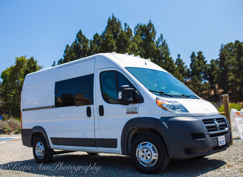 amidst other RVs and tents at a desert campsite.|Experience rv rental adventure: a woman opens a large portable fridge in a compact camper kitchen with a blue floral bed.|RV rental interior featuring a convenient portable cooler/fridge — photo 11