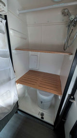 RV rental wet bath in a camper van, featuring a compact shower, toilet, and wooden slatted shelves.