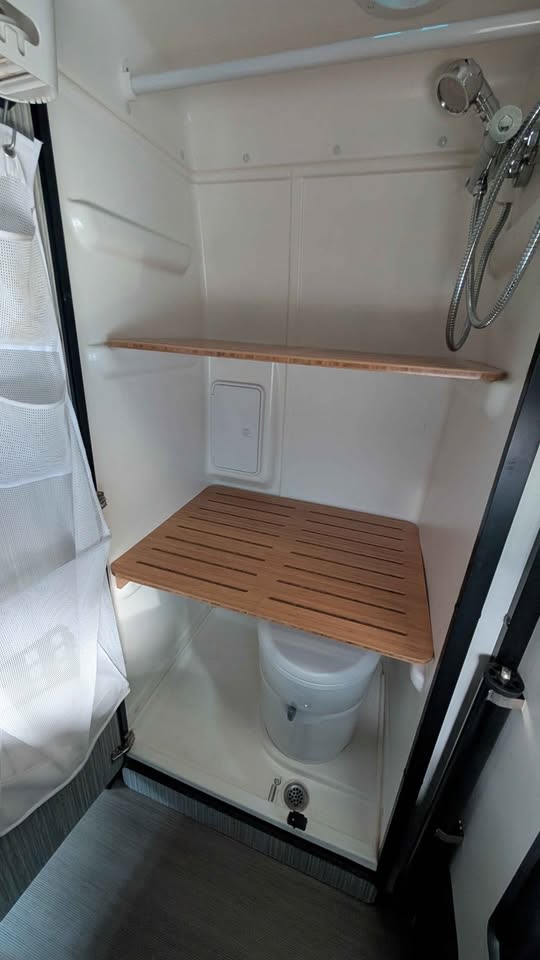  is parked near a building with a colorful circular face art and patches of snow.|This rv rental shows a cozy mobile office setup with a laptop on a swivel table — photo 3
