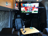 Cozy rv rental interior with a big screen TV showing sports, swivel chairs, and a small table. Ideal for travel entertainment.
