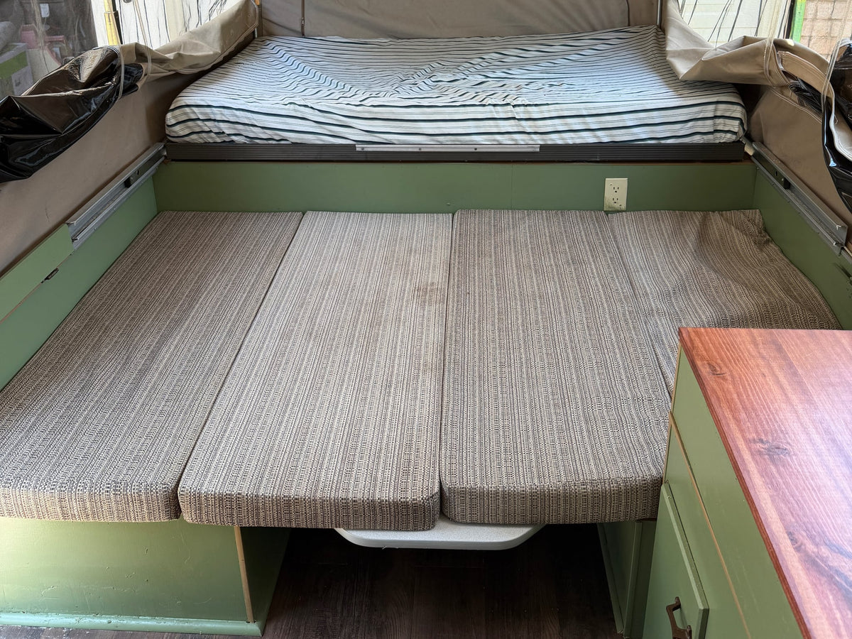  and wooden surfaces. Safety exit and extinguisher visible.|RV rental interior: a renovated pop-up camper with sage green cabinets — photo 7