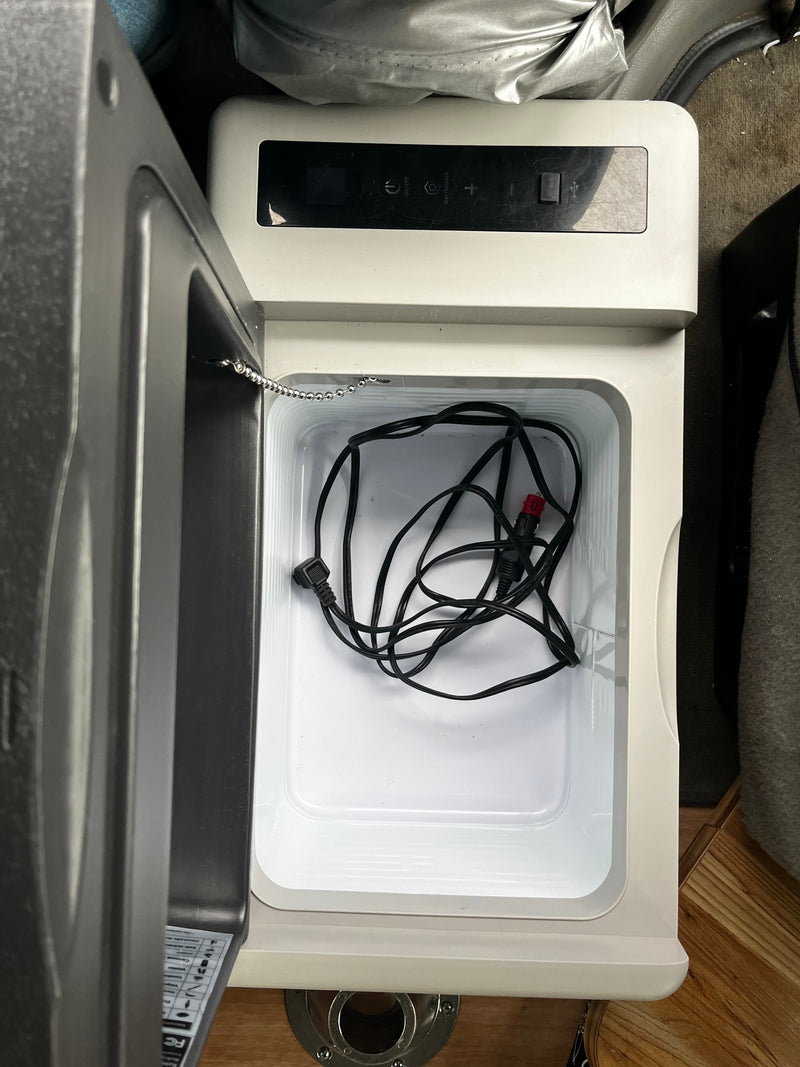 Open portable 12V car fridge/cooler inside an RV rental. View of interior with power cord and control panel, ready for use. — photo 13