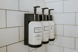 RV rental bathroom comfort: Wall-mounted Beekman 1802 shampoo & conditioner dispensers on white subway tile.
