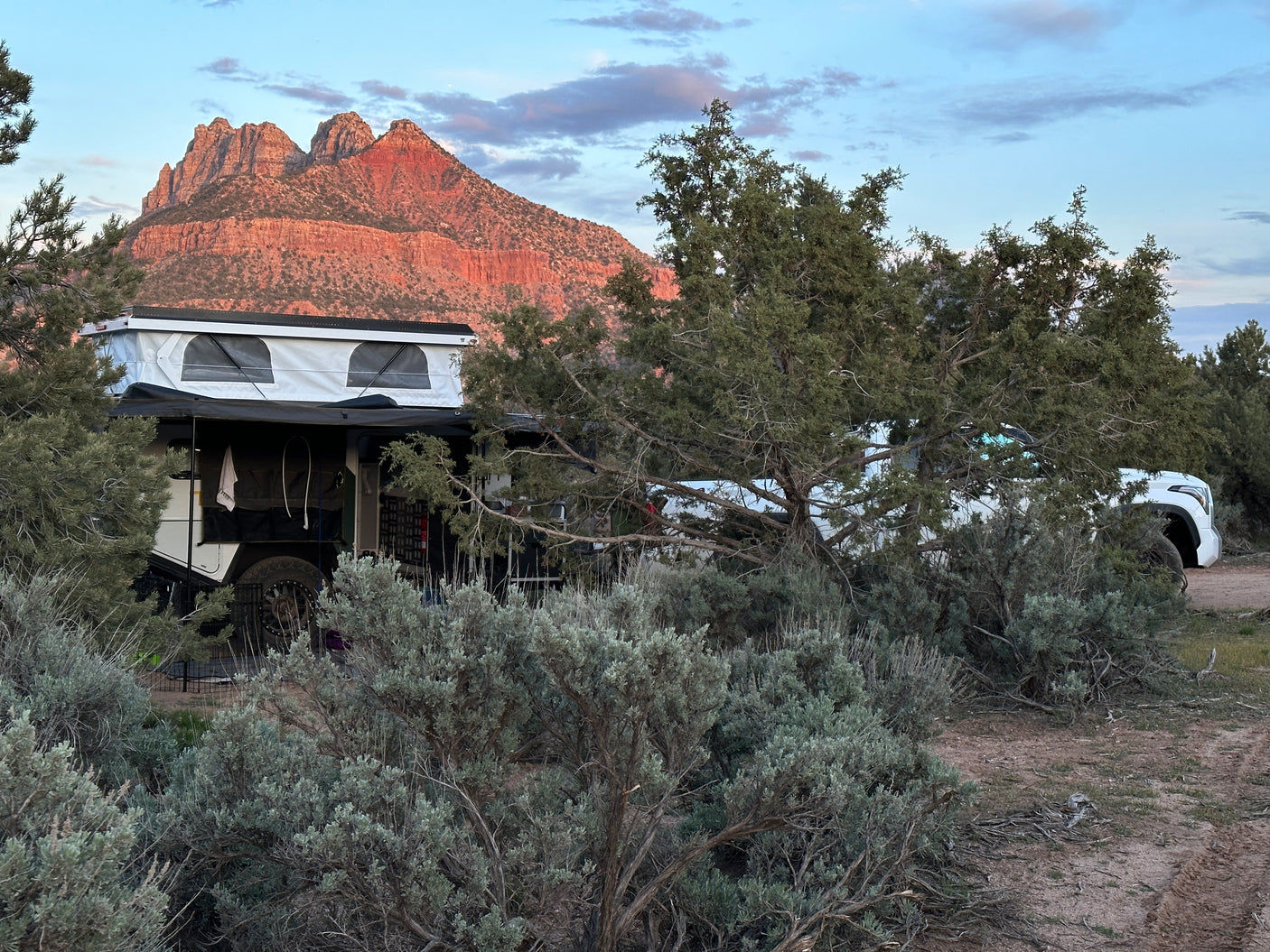RV rental camping with a pop-top trailer, truck, and majestic red mountains.