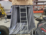 Spacious rooftop tent with ground annex & ladder, shown indoors. Enhance your rv rental camping or overlanding adventure.
