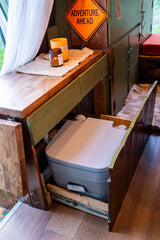 RV rental: Smart camper interior with a hidden pull-out toilet and cozy decor for adventure travel.