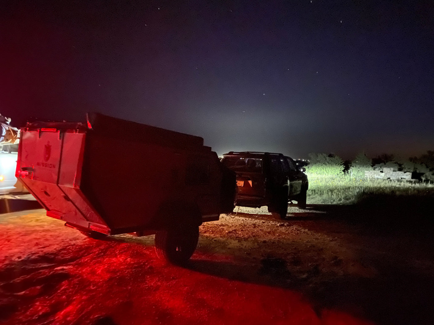  and truck with rooftop tent. Great for an RV rental adventure as kids play.|Stargazing under dark skies on an RV rental adventure! Our Mission Overland trailer & SUV ready for night camping.|A sunlit forest campsite features an RV rental expedition trailer