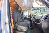 Experience our RV rental! The front cabin of a camper van conversion, featuring a comfortable swivel driver's seat, ready for the road.