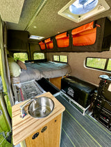 Adventure Wagon RV rental: comfy bed, compact kitchen w/ sink, stove & cooler. Ready for travel.